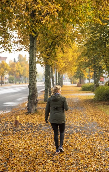Frau geht an der Straße im Herbst spazieren.