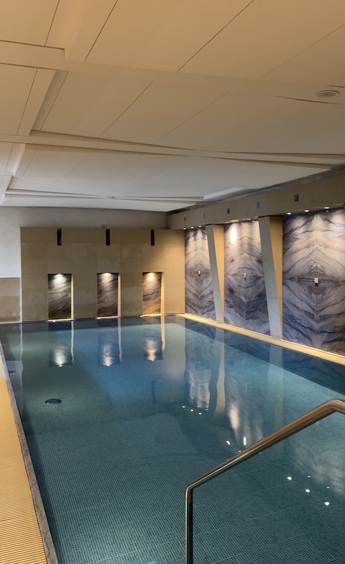 Pool gefüllt mit Wasser und Marmorfließen im Hintergrund.