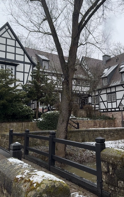 Aussenansicht von der Neumühle: Fachwerkhaus mit Brücke und Bach im Vordergrund.