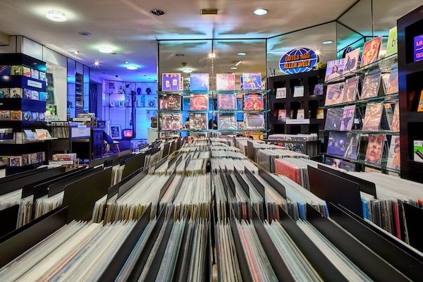 Platten nach Genre sortiert. Im Hintergrund besondere Platten in Regalen ausgestellt.