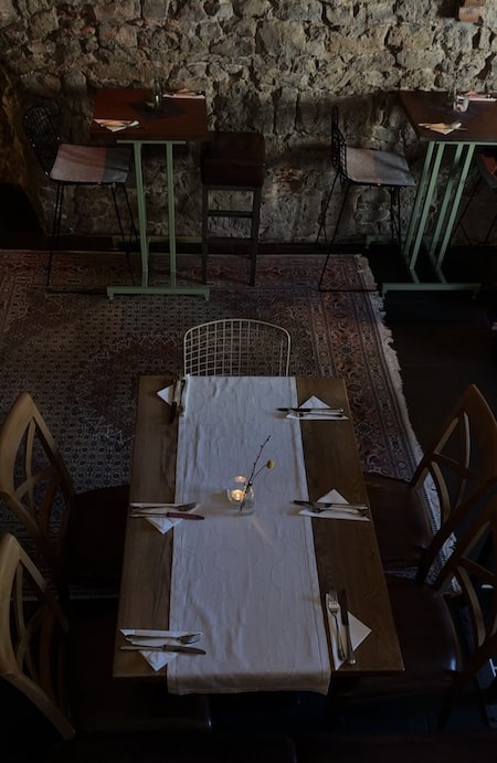 Blickwinkel von Oben: Holztisch mit braunen Stühlen und orientalischem Teppich auf dem Boden.