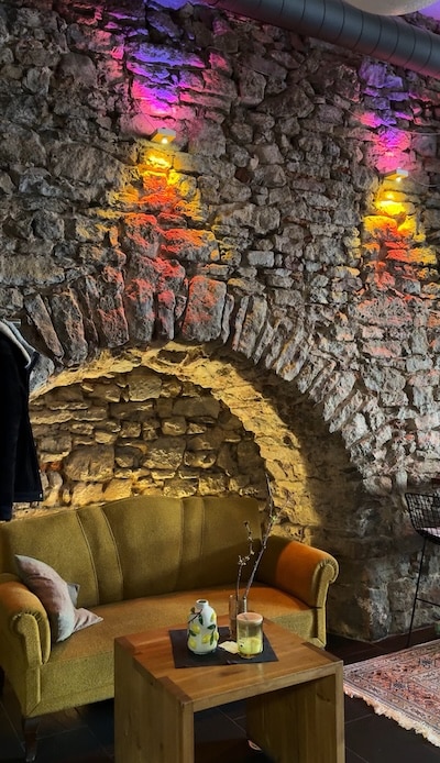 Grüngelbes Sofa steht hinter einem Couch-Tisch.